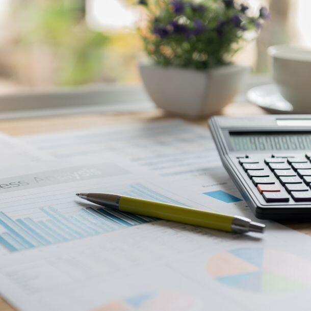 Pen, papers with graphs, and calculator on a desk