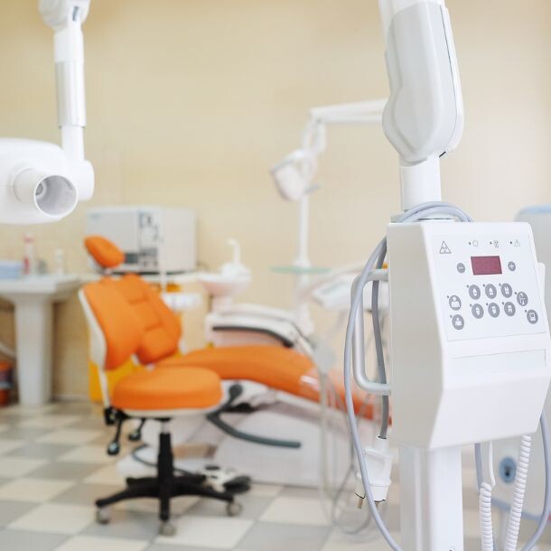 Orange patient chair at a dentist's office standing behind dentist lighting equipment