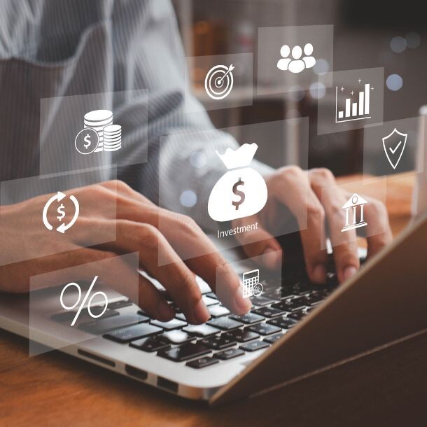 A person typing on a laptop keyboard while icons float on top of it. Some of the icons represent percentages, money, a group, and a shield.
