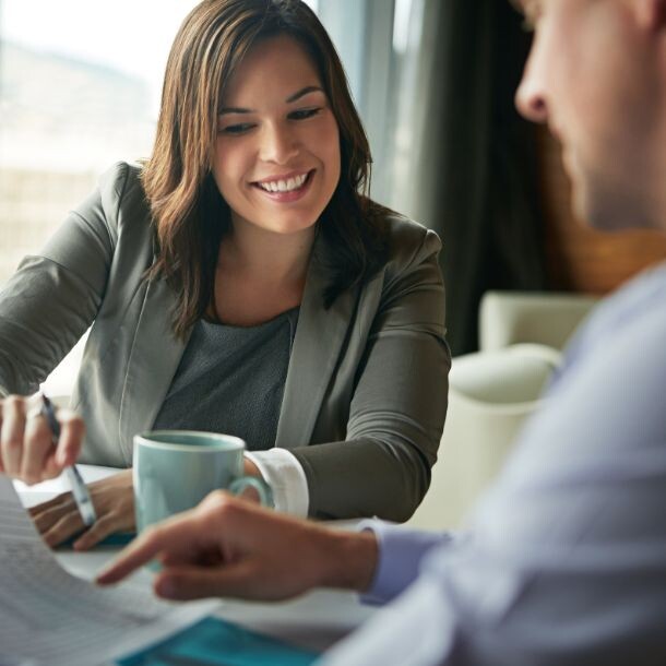 Women holding a pen sitting around a table showing another person something on a piece of paper
