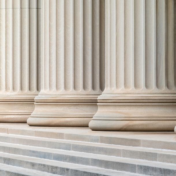 Light-colored stone columns sitting atop a set of stairs.