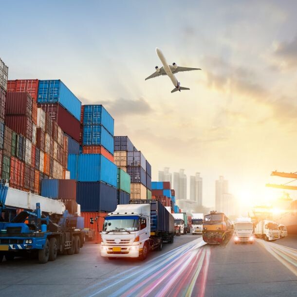 Standing in front of the surnise are large trucks, containers, a flying plane, and two large transporting ships.