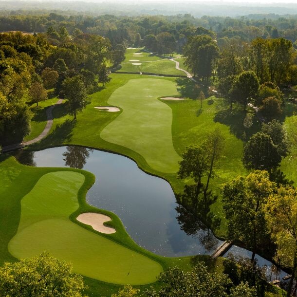 A golf course shot from a high view, with a lake in the middle.