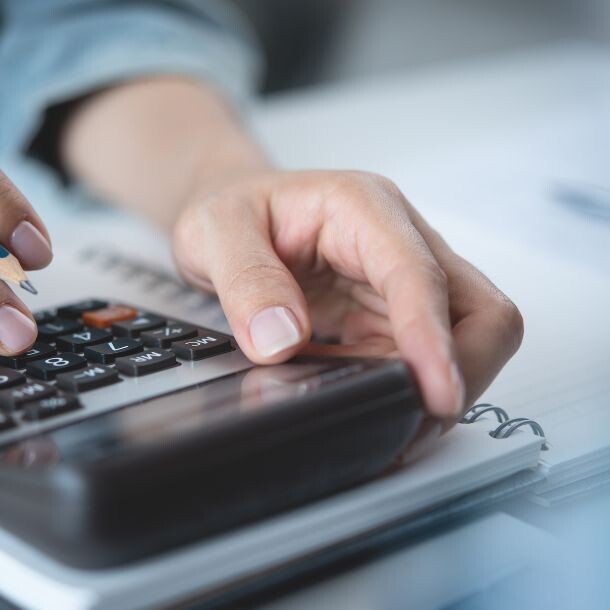Person using a calculator on top of a notebook.