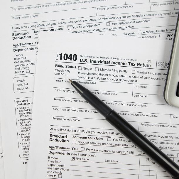 A few reports with a header that includes the code "1040;" on top of the reports sit a pen and a calculator.