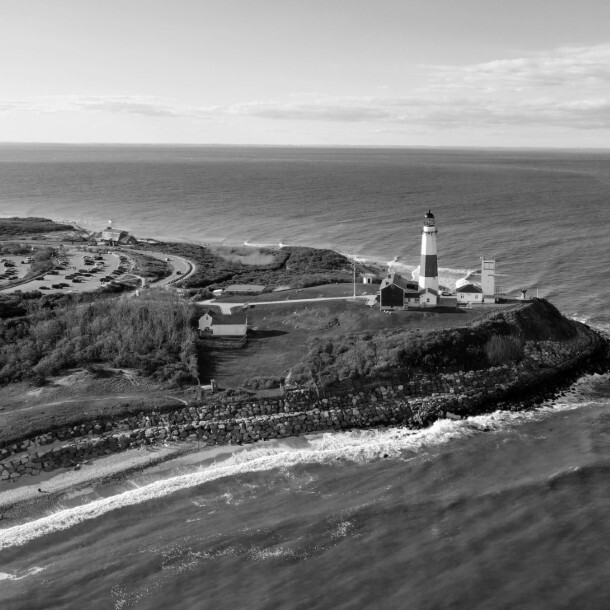 Aerial view of a lighthouse on a rocky coastline beside the ocean.
