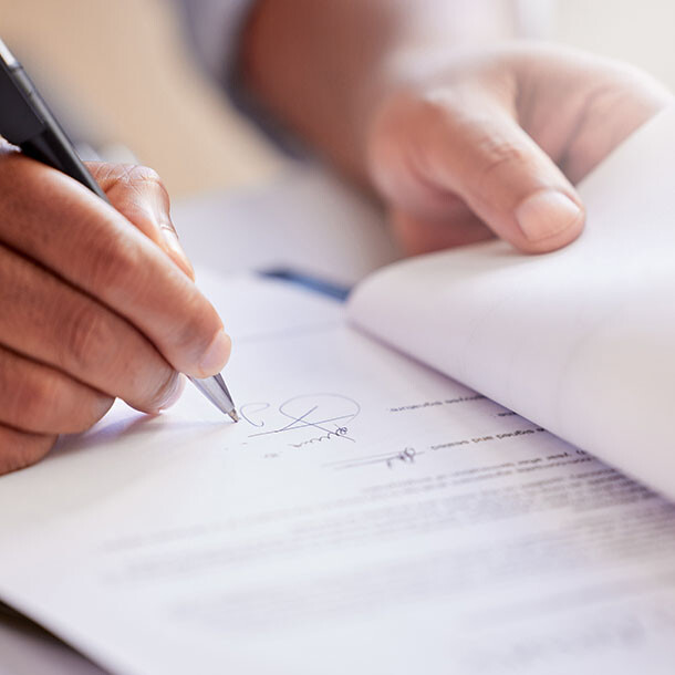 Close-up of a person signing a document with a pen