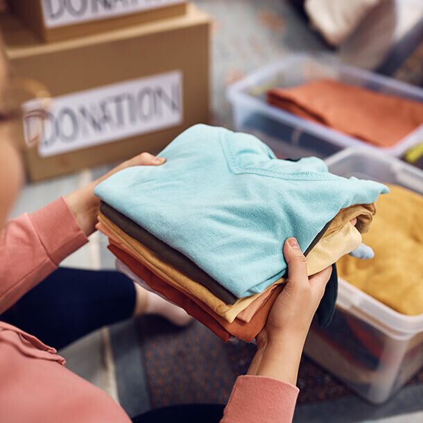 Woman sorting clothing into boxes for charity donation.