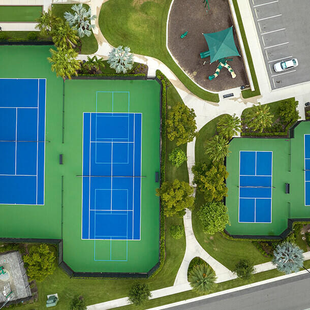 Aerial view of blue tennis courts representing private club recreational activity.