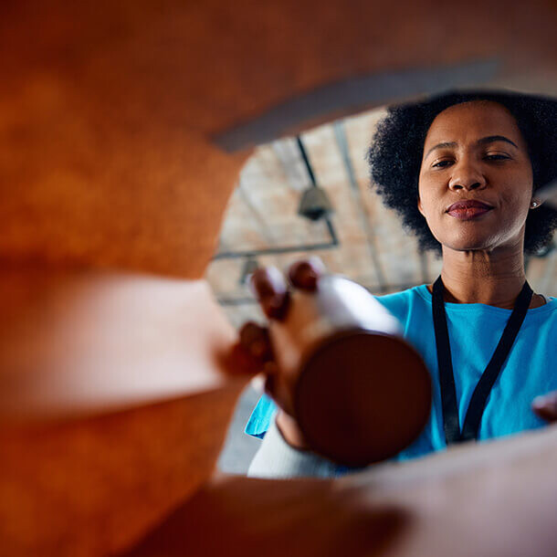 African American woman packing canned food while volunteering at a food bank.