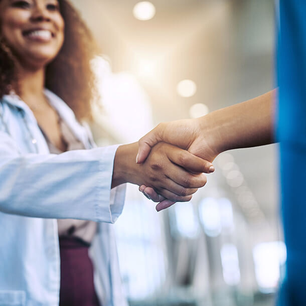 Doctor and nurse shaking hands in a hospital representing a professional partnership.