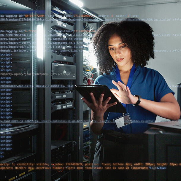 IT programmer using a digital tablet in server room for system updates at night.