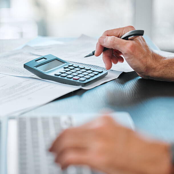 Calculator and laptop on desk representing tax review and financial planning.