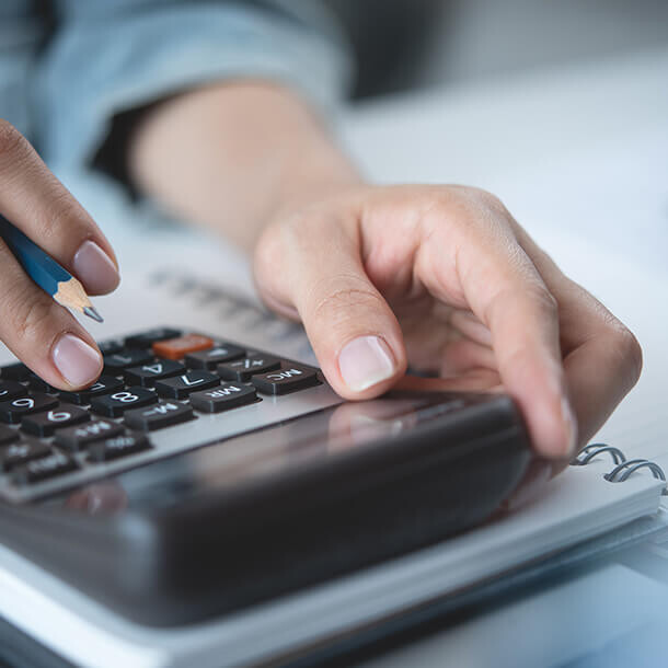 Woman using a calculator and writing notes representing home finance budgeting.