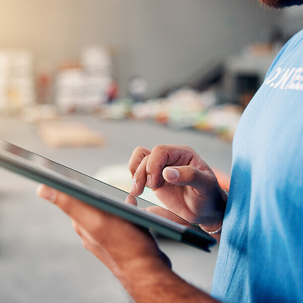 Volunteer using a tablet for non-profit inventory and food bank management.