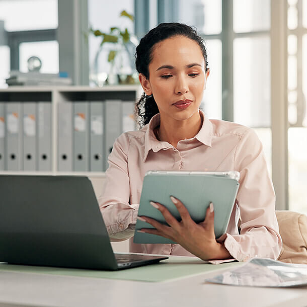 Business woman reviewing financial statements on a laptop in the office.