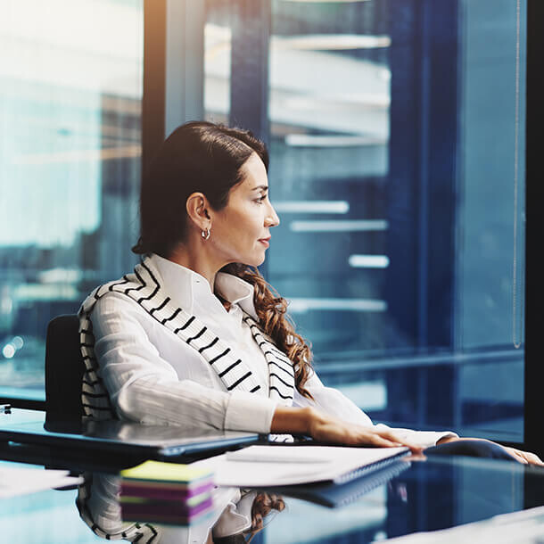 Businesswoman thinking by office window representing financial decision-making.
