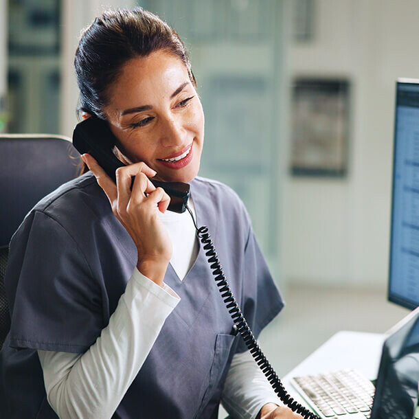 Female doctor smiling while on a phone call at a hospital.