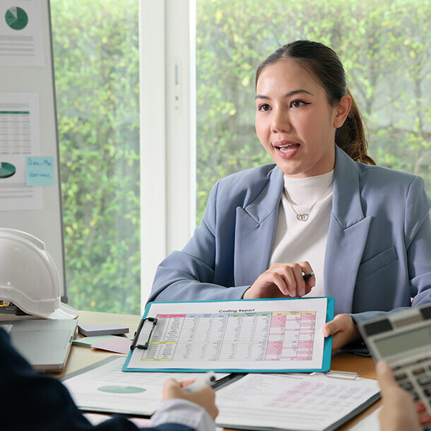 Asian businesswoman reviewing cost variance and income tax data at an audit office.