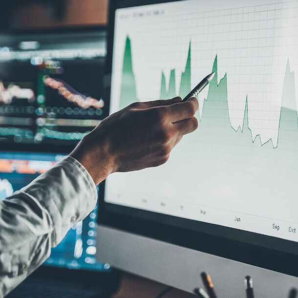 Businessman pointing at a chart in a creative office representing investment banking data analysis.